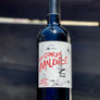 A bottle of red wine labeled 'Los Conejos Malditos' with a graphic illustration on the label, held in front of a blue background.