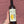 Bottle of Baia's Wine Tsolikouri held against a textured red brick wall.