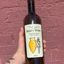 Bottle of Baia's Wine Tsolikouri held against a textured red brick wall.