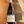 A hand holding a bottle of Bernard Demaille Chablis 2024 white wine against a warm-toned painting of a sailing ship.
