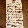 A handwritten paper tag on a wooden surface listing flavor and ingredient details for Biscaris Sicily 100% Frappato Sicily.