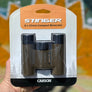 Carson Stinger 8 x 22mm compact binoculars in packaging held by a hand with a blurred natural background.