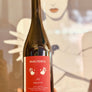 Wine bottle labeled 'Pain Perdu' held in front of a blurred background