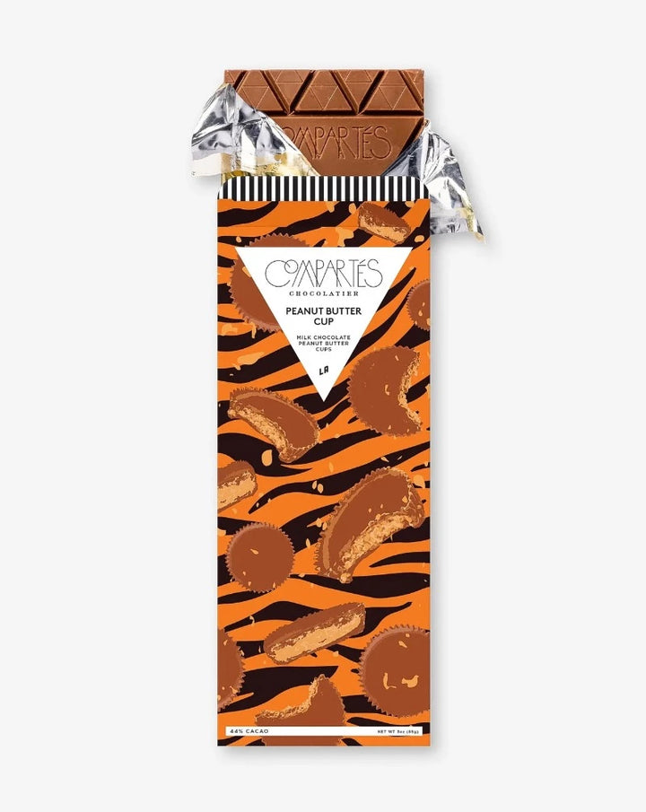 Introducing our latest creation: the decadent Peanut Butter Cup chocolate bar. Indulge in Compartés peanut butter cups wrapped in creamy milk chocolate, in chocolate bar form. This is the most decadent marriage of peanut butter and chocolate. Featuring striking black and orange graphics, this is a modern twist on a classic that keeps you coming back for more... and more...