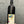 Wine bottle with a colorful label featuring an artistic face design on a gray background