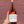 Bottle of Enkidu Rosé wine held against a textured red brick wall.