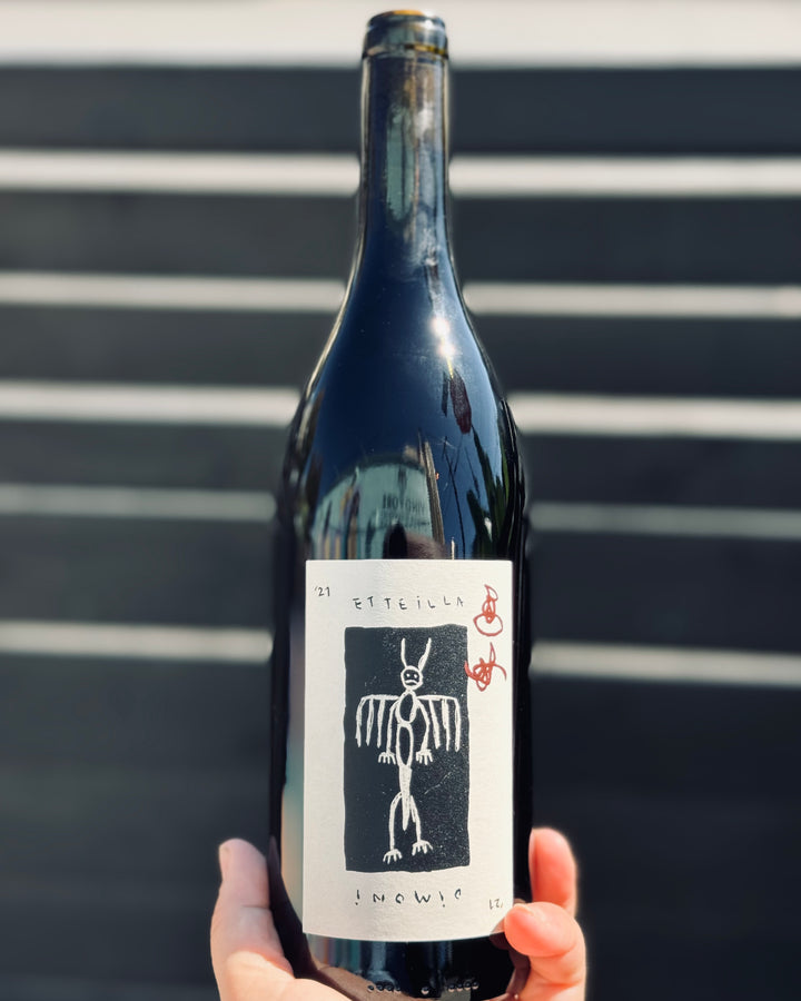 Wine bottle with a unique label held against a striped background