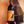 A hand holds a dark wine bottle with a bright orange label that reads 'FINAL GIRL' and 'SANGIOVESE 2024' against a warm brown background with a ship illustration.