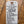 A white paper hangtag with handwritten text listing wine ingredients and descriptions, tied with a white string and placed on a wooden surface.