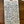 A handwritten kraft paper tag with a hole and white string, placed on a wooden surface. The tag lists ingredients and notes for a product titled "High Camp 'Happy Canyon'" in cursive handwriting.