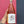 Bottle of rose wine held by a hand against a pink and blue background