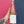 Bottle of rosé wine held by a person with a tattooed arm against a pink and blue background