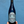 A bottle of BK Wines Carbonic Pinot Noir with a label that includes the brand name and the variety 'Pinot Noir'. The background is blue, and the bottle is held by a hand.
