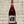 Bottle of Land Mass Chillable Red wine held against a textured wall.