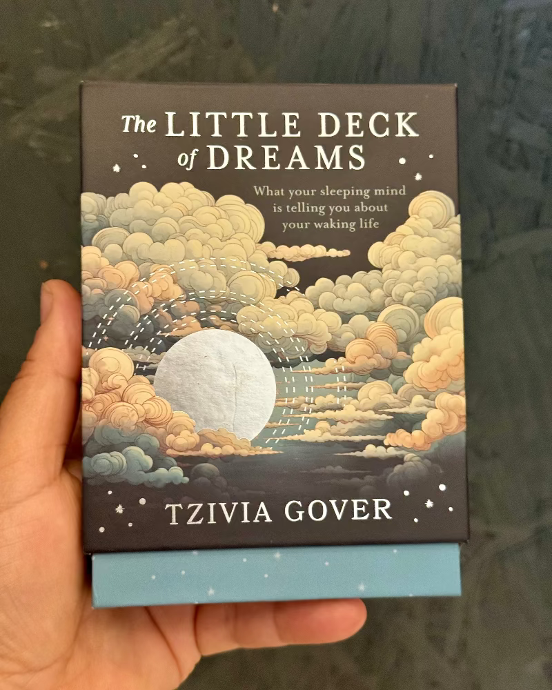 Book titled 'The Little Deck of Dreams' by Tzivia Gover held in a hand with a blurred background