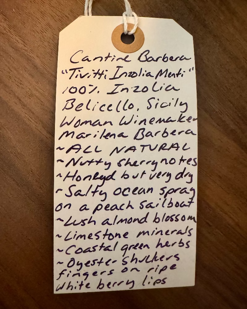 Handwritten tag with wine description on a wooden surface