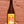 Bottle of Pulpe fashion with a yellow label against a brick wall.