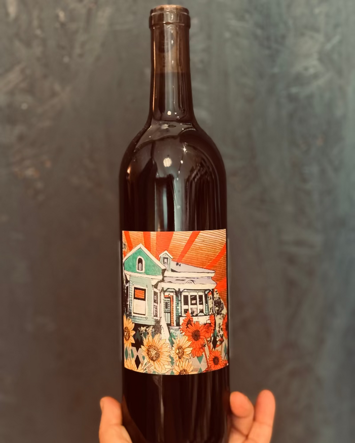 Wine bottle with a colorful label featuring a house and flowers against a dark background