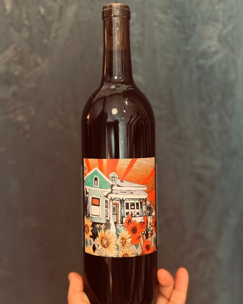 Wine bottle with a colorful label featuring a house and flowers against a dark background