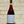 Bottle of red wine with a patterned label held against a textured wall.