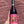 Wine bottle with a pink label featuring a zodiac design held against a brick wall.