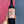 Wine bottle held by a hand with a colorful label against a pink and blue background