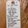 Handwritten tag on a wooden surface with product details.