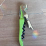 Corkscrew with green handle on a wooden surface