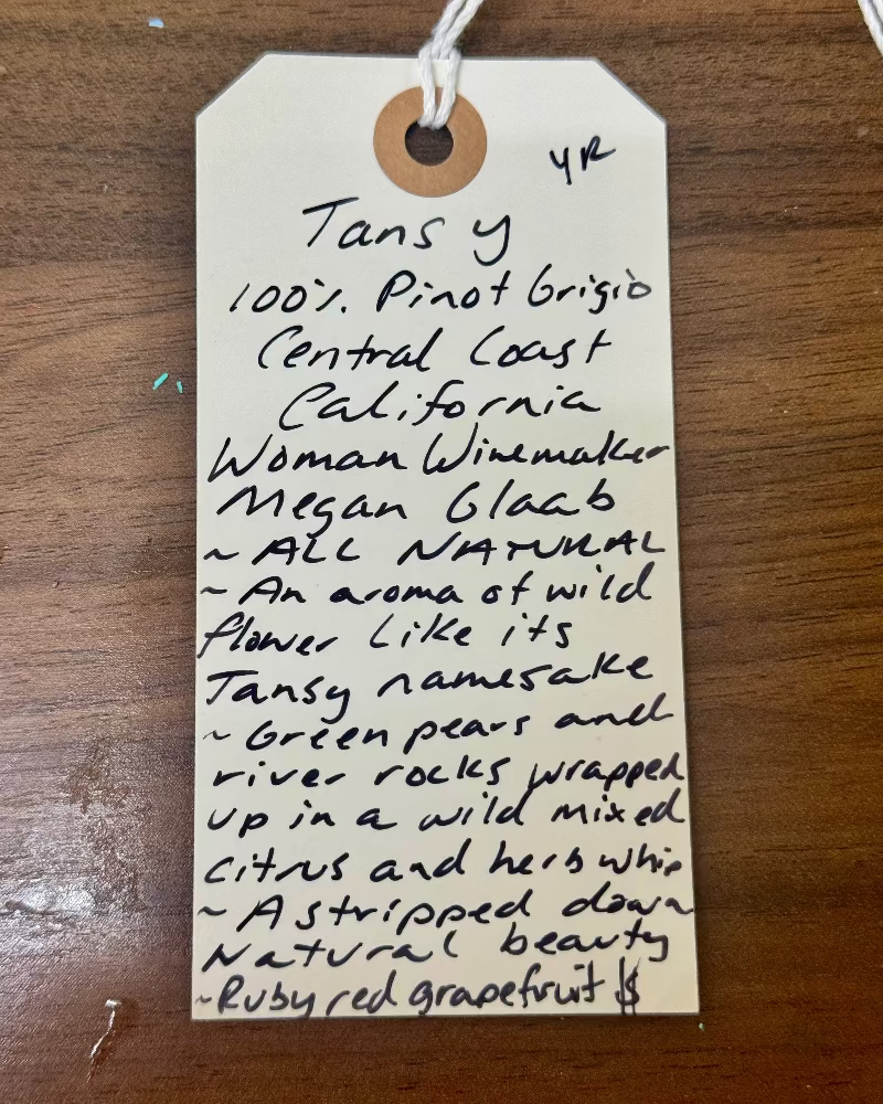 Wine label with handwritten description on a wooden surface