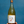 Wine bottle with a label featuring artistic design held against a blue background
