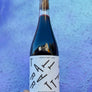 Bottle of wine with a white label held against a textured blue background