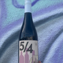 Bottle of wine with a label '5/4' held against a textured blue and purple background