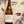 Wine bottle labeled 'ENKIDU' held in front of a stylized face artwork.