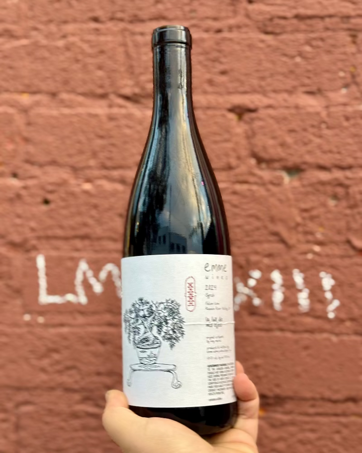 Wine bottle held in front of a textured red brick wall