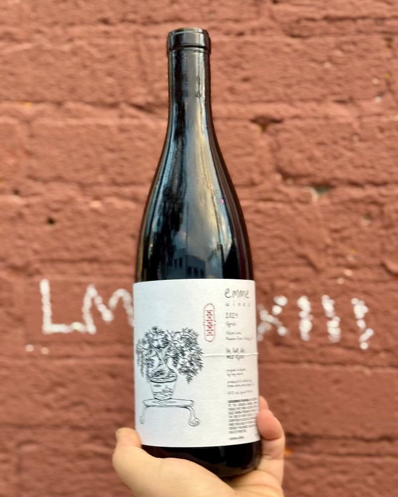 Wine bottle held in front of a textured red brick wall