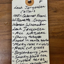 Handwritten tag on a wooden surface with product description