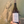 Bottle of wine labeled 'tre' held in front of a decorative wall with horse sculptures.