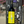 Wine bottle with a yellow label featuring a cartoon character, held in front of a chalkboard with writing.