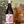 Bottle of wine with a decorative label held in front of a scenic painting.
