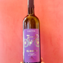 Wine bottle with purple label featuring a bicycle design, held against a red background.