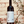 Bottle of Krya wine held in front of a textured wall with greenery.
