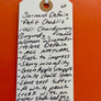 Handwritten wine label on a white tag against an orange background