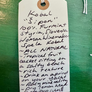 Handwritten tag on a green background with wine description text