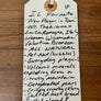 Handwritten tag on a wooden surface with product description
