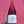 A hand holding a bottle of Kareen Barbera Rosato rosé wine against a bright pink textured wall. The bottle has a white label with a purple illustration of a fish and the brand name 'KAREEN' at the top.