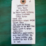White tag with handwritten text on a green background