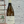 Wine bottle labeled 'Marsanne' held against a textured wall.