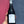 A hand holding a bottle of Mirgin Reserva 2021 red wine, set against a split pink and dark blue textured wall.
