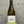 A hand holding a bottle of Ostatu Rioja Alavesa Blanco 2020 white wine against a textured gray concrete wall.