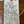 A handwritten white paper price tag with a wooden dowel hole and string, showing recipe details for 'Ostatu Rosado' jam on a wooden surface.